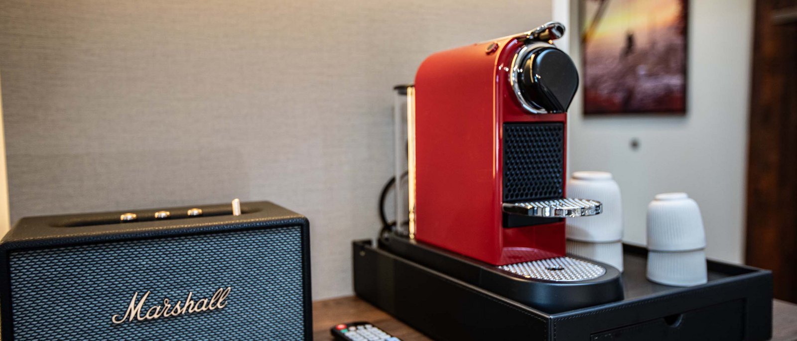 Executive Room Roter Kaffeeautomat neben Marshall Lautsprecher und Fernbedienung auf Holztisch