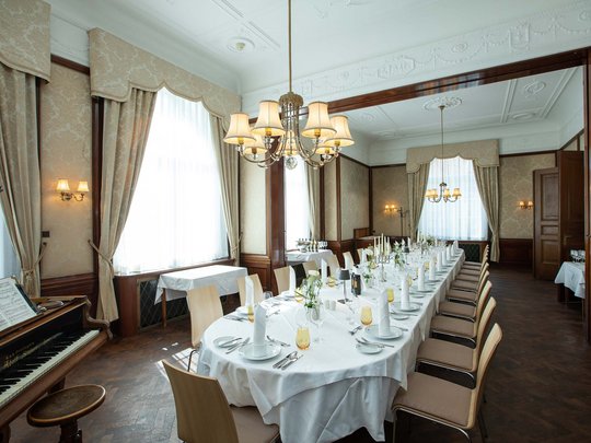 Hotel Böhlerstern: the dining room in the  Fürstentrakt Elegant dining table with white tablecloth and piano in classic dining room