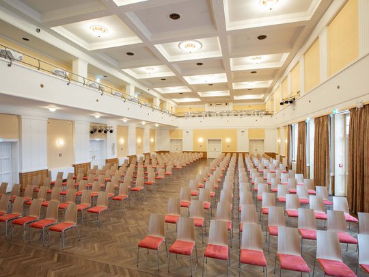 Seminarräume im Hotel Böhlerstern: der Theatersaal Leerer großer Saal mit vielen in Reihen aufgestellten Holzstühlen mit roten Sitzen