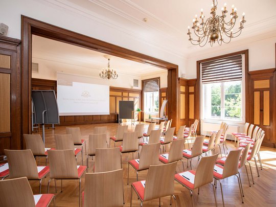Seminar rooms at Hotel Böhlerstern: club room Bright conference room with rows of chairs, projector, and large windows