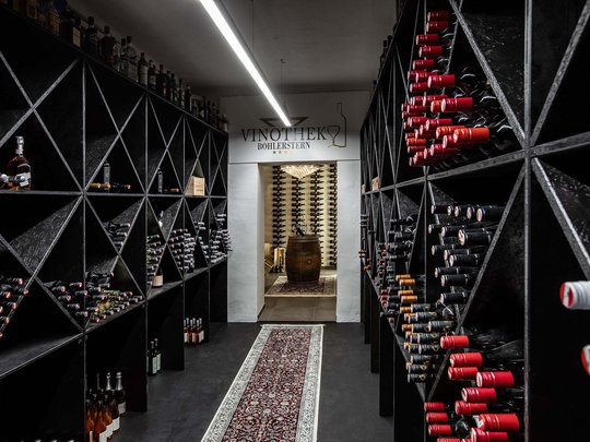 Seminar rooms at Hotel Böhlerstern: our Genusslabor® Wine cellar with black racks filled with wine bottles in wine shop
