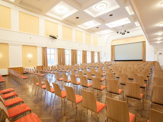 Seminarräume im Hotel Böhlerstern: der Theatersaal Leerer Konferenzsaal mit Holzstühlen und einer großen Leinwand vorne