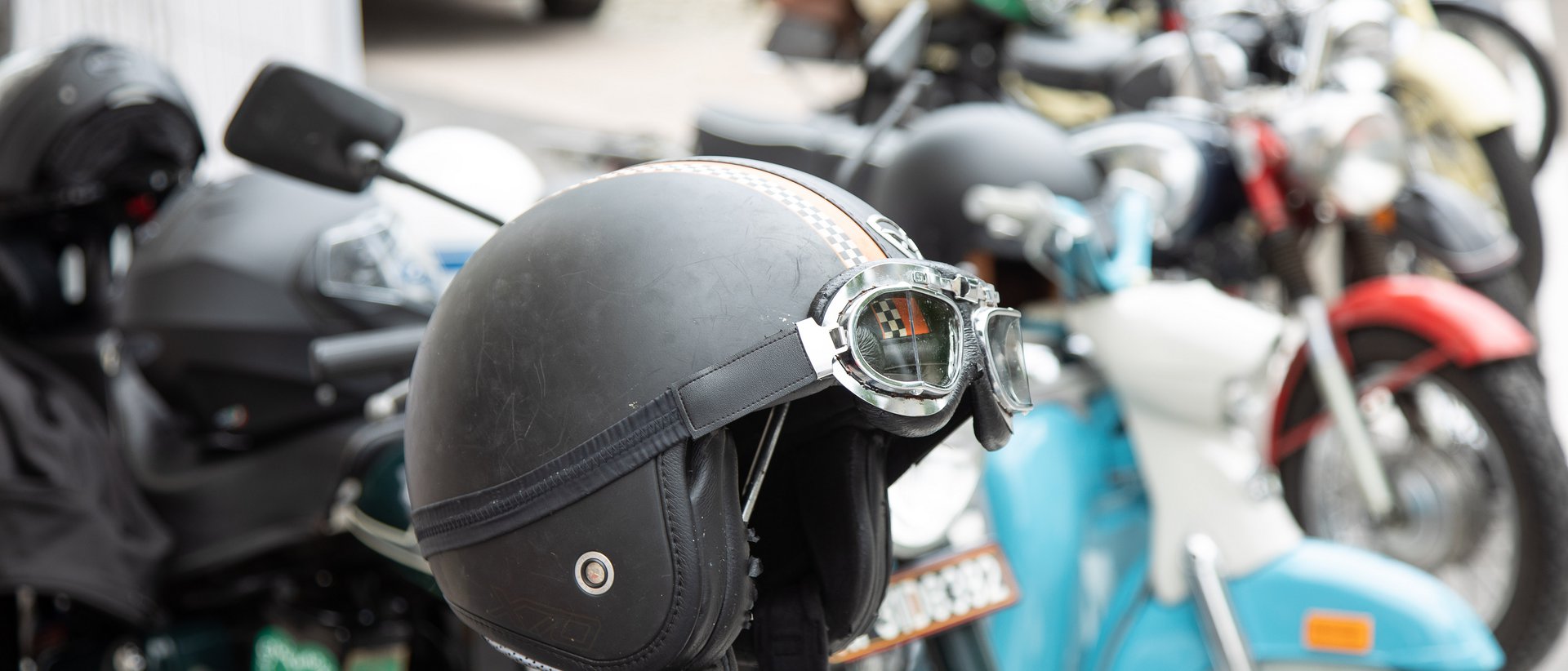 Motorrad Package Schwarzer Motorradhelm mit Schutzbrille an geparktem Motorrad