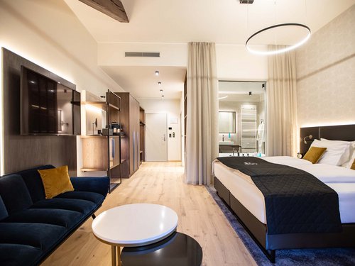 Double room Modern hotel room with large bed, sofa, TV, and light wooden flooring
