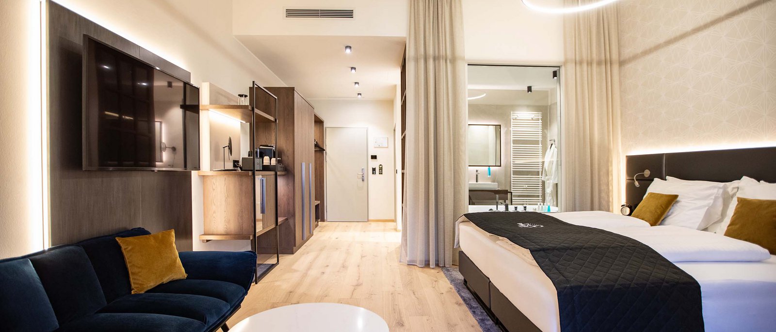 Executive Room Modernes Hotelzimmer mit großem Bett, Sofa, TV und hellem Holzfußboden