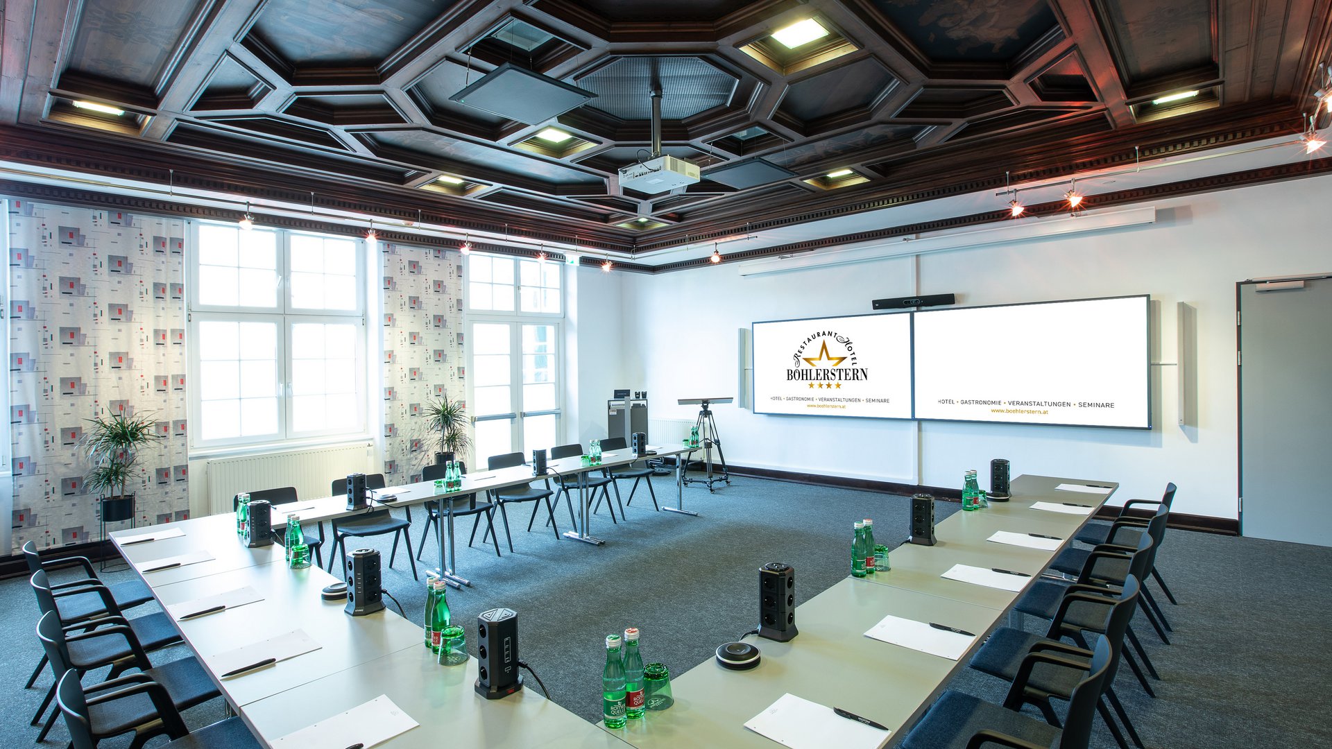 Meeting rooms at Hotel Böhlerstern: video conference room Bright seminar room with U-shaped tables, chairs, water bottles, and projector screen