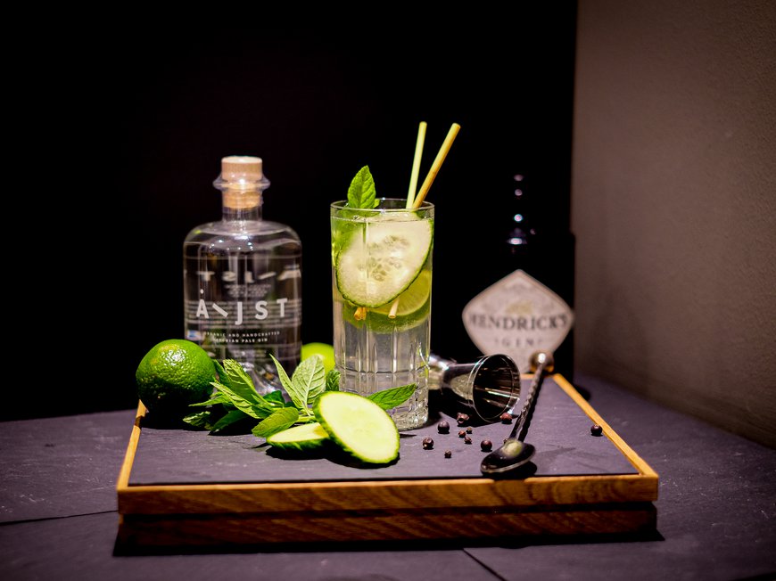 Cuisine at Hotel Böhlerstern Gin cocktail with cucumber slices, lime, mint, and gin bottles on a wooden tray