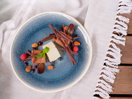 Private Feiern im Hotel Böhlerstern Dessert mit Schokolade, Beeren und Minzblatt auf blauem Teller