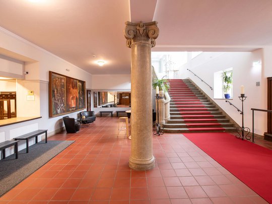 Seminarräume im Hotel Böhlerstern: der Theatersaal Heller Innenraum mit Säule, roten Teppichstufen und Sitzecke mit Kunstwerken