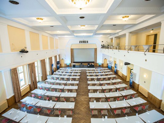 Seminarräume im Hotel Böhlerstern: der Theatersaal Großer heller Konferenzraum mit Reihen von Tischen und Stühlen vor Leinwand