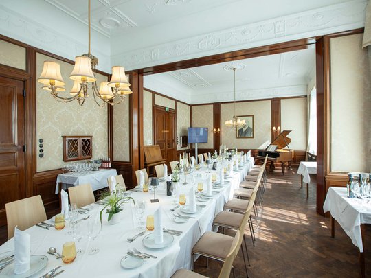 Private Feiern im Hotel Böhlerstern Eleganter Speiseraum mit langem gedecktem Tisch und Flügel im Hintergrund