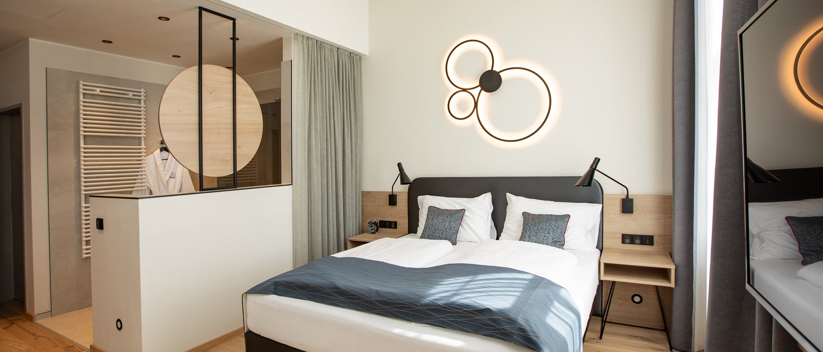 Deluxe double room Modern hotel room with double bed, unique wall light, and wooden floor