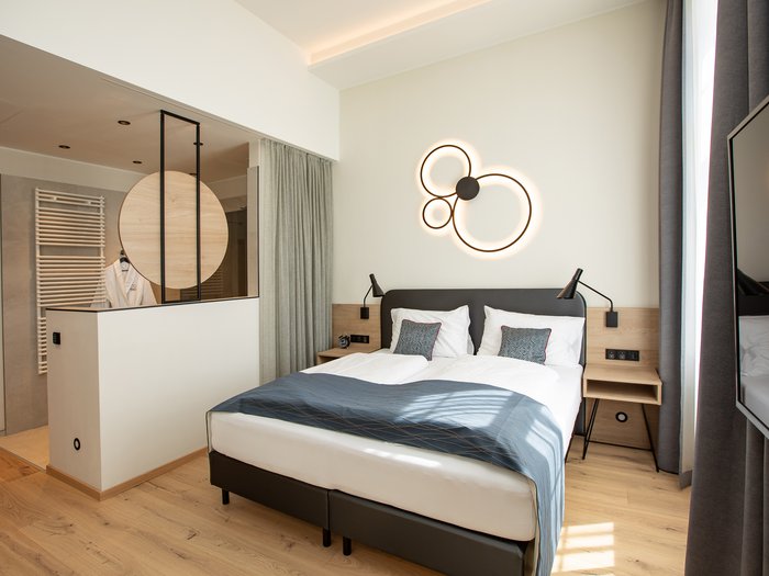 Hotel Böhlerstern in der Steiermark: unsere Zimmer Modernes Hotelzimmer mit Doppelbett, origineller Wandlampe und Holzboden