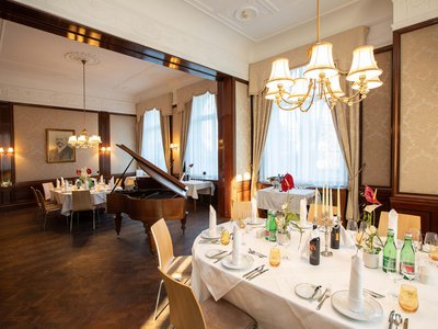 Hotel Böhlerstern: the dining room in the  Fürstentrakt Elegant dining room with set table and grand piano in historic setting