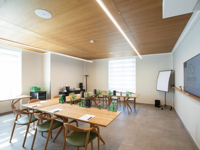 Emil Moderner Meetingraum mit Holztischen, Stühlen, Flachbildschirm und Flipchart