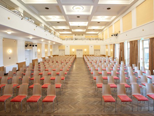 Seminarräume im Hotel Böhlerstern: der Theatersaal Leerer großer Veranstaltungssaal mit Reihen von Stühlen mit roten Sitzen