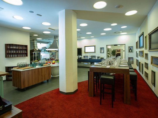Seminar rooms at Hotel Böhlerstern: our Genusslabor® Modern dining area with a long wooden table and a view into the kitchen