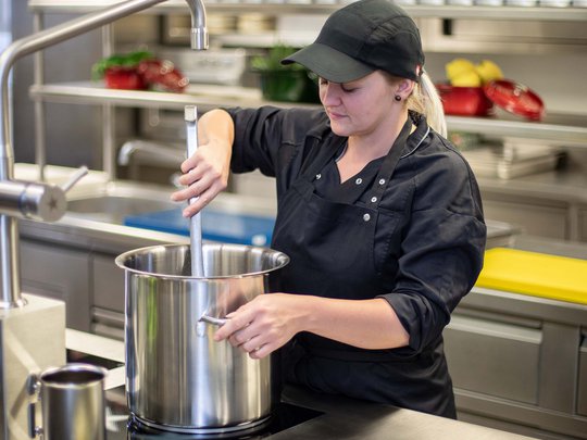 Seminar rooms at Hotel Böhlerstern: our Genusslabor® Chef stirring large pot in professional kitchen with fresh fish on ice in foreground