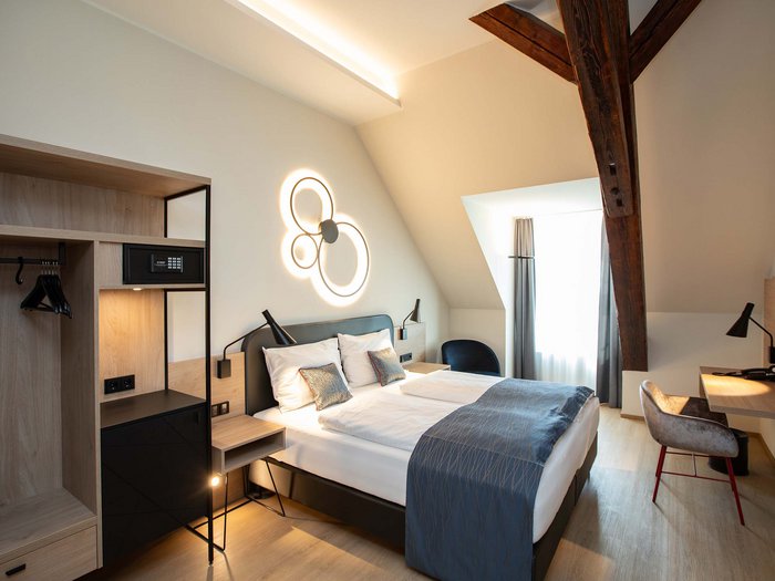 Hotel Böhlerstern in der Steiermark: unsere Zimmer Modernes Hotelzimmer mit Doppelbett, Schreibtisch und Holzbalken an der Decke