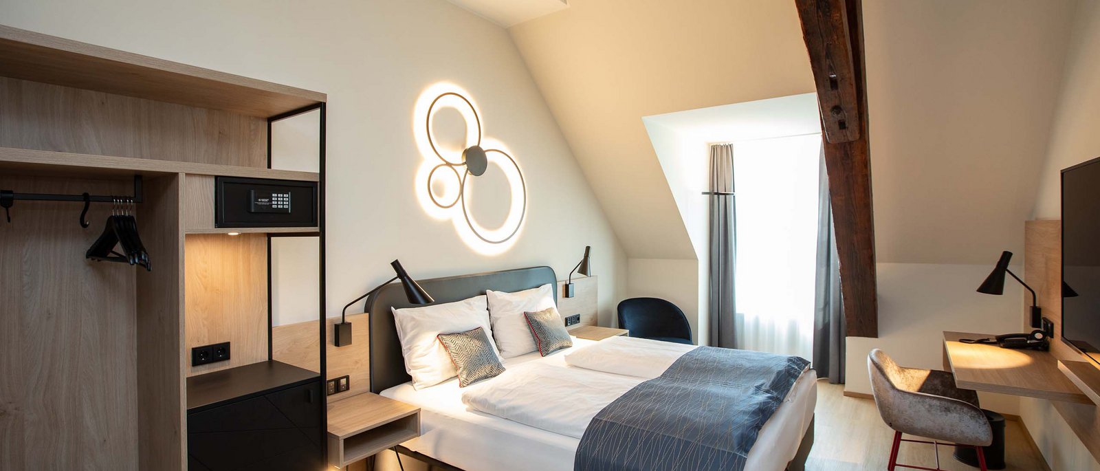Double room Modern hotel room with double bed, desk, and wooden ceiling beams