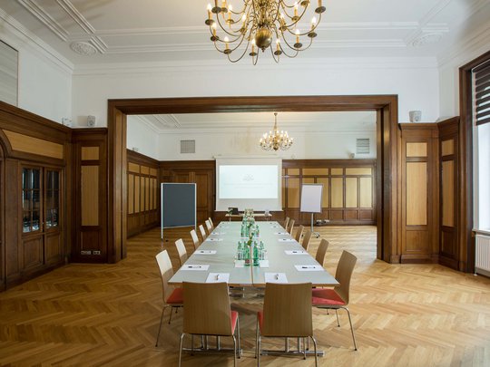 Seminar rooms at Hotel Böhlerstern: club room Large conference room with wood paneling, tables, chairs, and presentation equipment