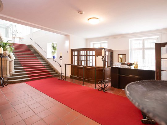 Seminarräume im Hotel Böhlerstern: der Theatersaal Treppenhaus mit rotem Teppich und Empfangstresen in einem klassischen Gebäude