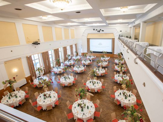 Seminarräume im Hotel Böhlerstern: der Theatersaal Großer festlich dekorierter Saal mit runden Tischen und Blumenarrangements