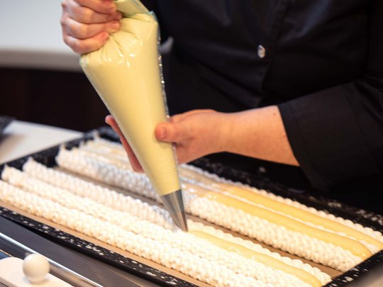 Seminar rooms at Hotel Böhlerstern: our Genusslabor® Person piping batter with a bag into baking tray lined with white cream