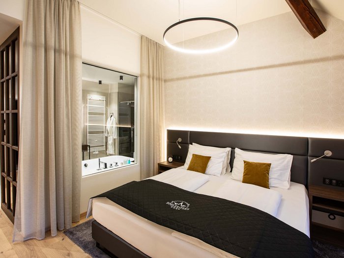 Hotel Böhlerstern in der Steiermark: unsere Zimmer Modernes Hotelzimmer mit Doppelbett und Badezimmer durch Glaswand sichtbar