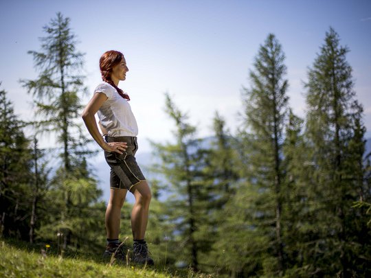 Our tips: the best trips in Styria Woman in traditional shorts stands in forest looking into the distance