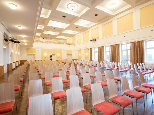 Seminarräume im Hotel Böhlerstern: der Theatersaal Großer Saal mit vielen Stühlen mit roten Sitzpolstern in Reihen