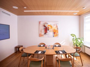 Seminarhotel Böhlerstern: die wichtigsten Infos zum Download Essbereich mit ovalem Holztisch, sechs Stühlen und moderner Kunst an der Wand