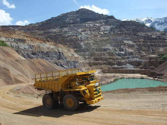 Our tips: the best trips in Styria Large yellow dump truck in a quarry with layered rock walls and a water pool