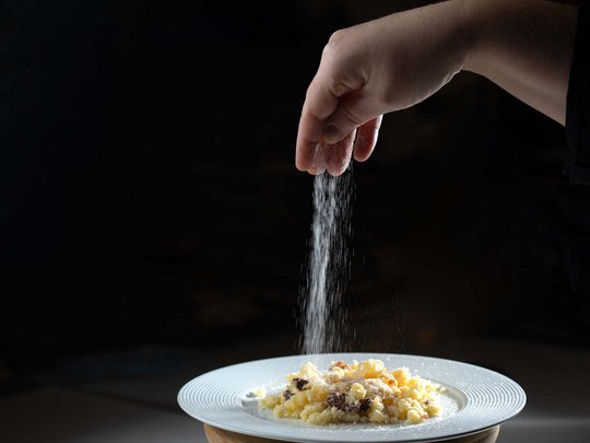 Seminar rooms at Hotel Böhlerstern: our Genusslabor® Hand sprinkling salt over a dish on a white plate against a dark background