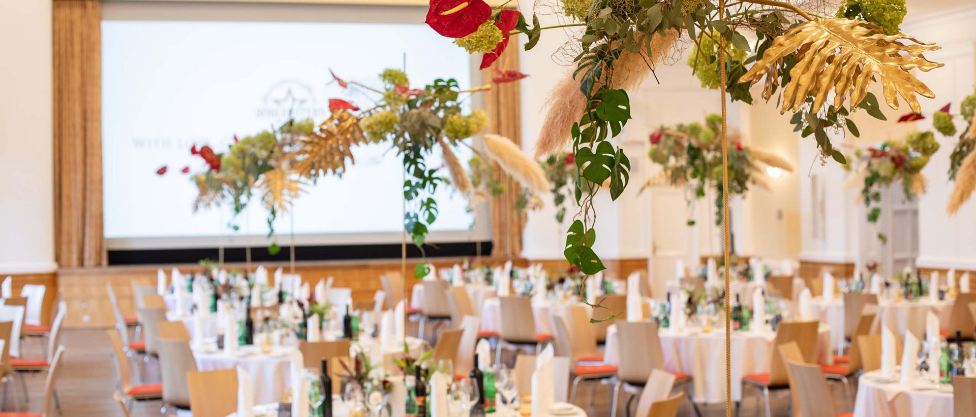 Events 2025 Festively decorated banquet hall with round tables and floral arrangements