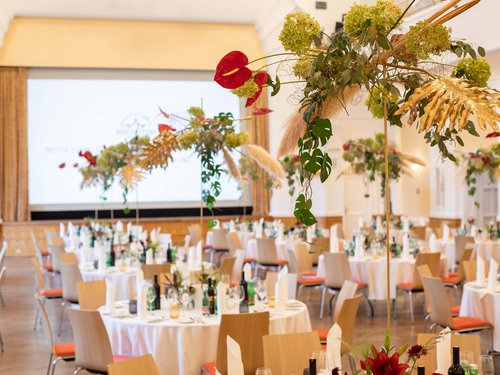 EARLY BIRD DEAL Festively decorated banquet hall with round tables and floral arrangements
