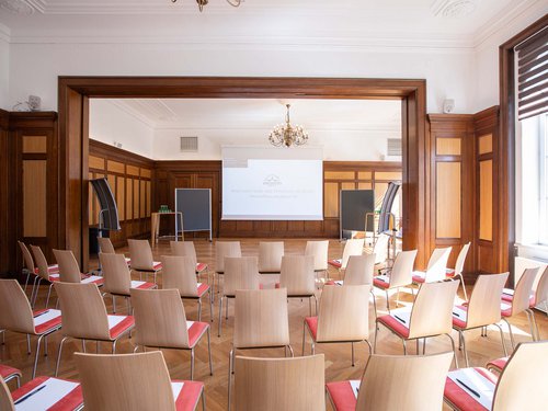 EARLY BIRD DEAL Classic seminar room with chairs, projector screen, and flip charts
