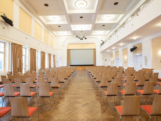 Seminarräume im Hotel Böhlerstern: der Theatersaal Leerer großer Konferenzraum mit Reihen von Stühlen und großer Leinwand